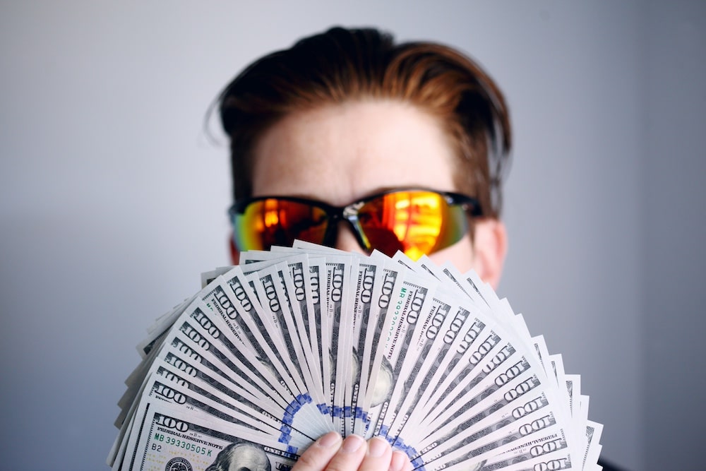 A man partially covering his face with cash.